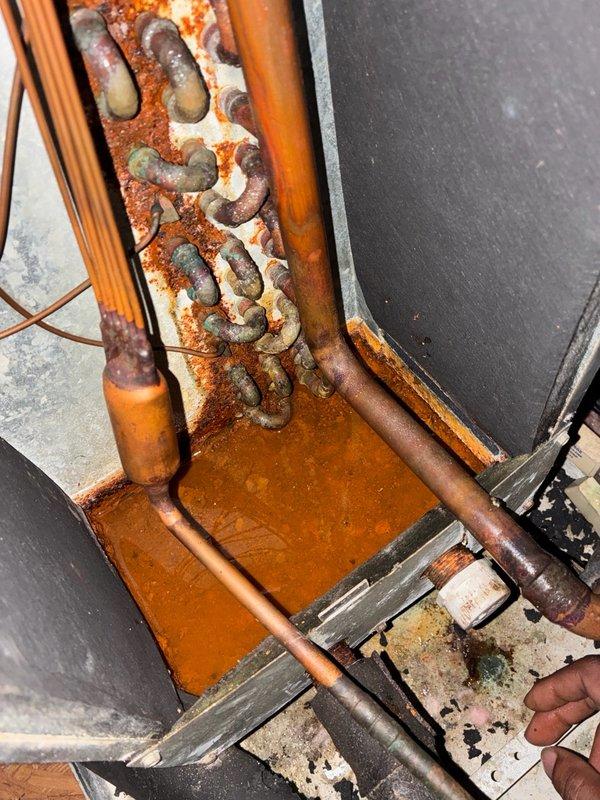 # Dispatch Summary

Responded to cooling complaint with unit experiencing daily temperature rise and intermittent freeze-ups. Upon arrival, conducted visual inspection of HVAC system revealing extensive rust and corrosion on refrigerant lines, mounting brackets, and condensate pan. Heavy oxidation present on copper piping connections and metal framework, indicating prolonged moisture exposure. Documented equipment condition with photographs showing significant deterioration of components including corroded drip pan, oxidized copper lines, and rusted support structures. Unit requires further diagnostic evaluation to determine root cause of cooling issues and assess impact of corrosion on system performance and refrigerant integrity.