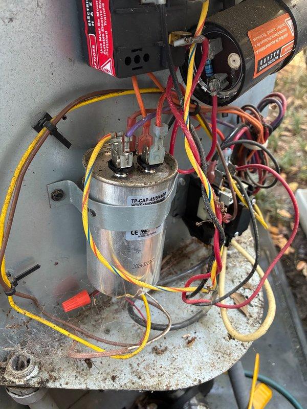 Responded to after-hours dispatch for downstairs air conditioning system blowing warm air while upstairs system operated normally. Performed diagnostic testing on outdoor condensing unit, including electrical measurements of capacitor and motor components using clamp meter. Inspected internal electrical compartment, evaluating capacitor condition, wiring connections, and motor operation. Measured amperage draw at 0.78 amps on system components to assess operational status and identify cooling failure cause.