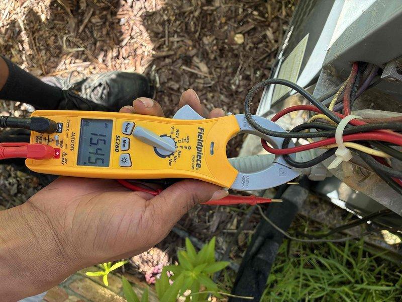Completed large-scale repair addressing water intrusion issue caused by improper condensate drain line installation with insufficient pitch running beneath the HVAC unit. Performed electrical diagnostics using digital multimeter and clamp meter to verify system operation, measuring voltage and amperage at control panel and outdoor unit connections. Rerouted and re-pitched condensate drain line to establish proper gravity flow and prevent water backup into equipment cabinet, though complete resolution pending full drying period to assess effectiveness of drainage modifications.