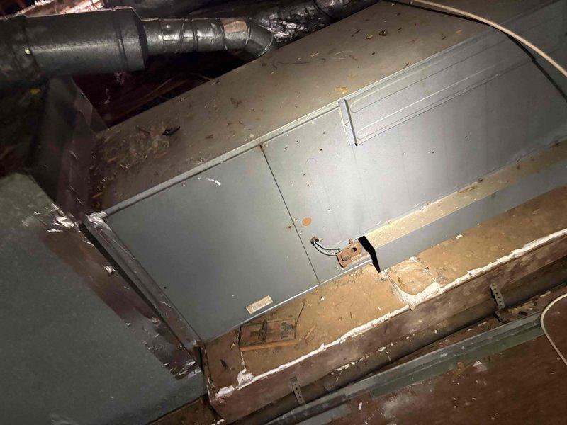 Responded to after-hours dispatch for no cooling complaint with indoor temperature at 74°F and thermostat set to 70°F. Accessed attic-mounted air handler unit and inspected HVAC system components, including ductwork and equipment condition. Documented existing installation showing air handler with accumulated dust and debris, reflective insulated supply ducts, and pink fiberglass batt insulation between joists. System had previous refrigerant service during last cooling season, indicating potential recurring leak or compressor issue requiring further diagnostic evaluation during regular business hours when customer becomes available.