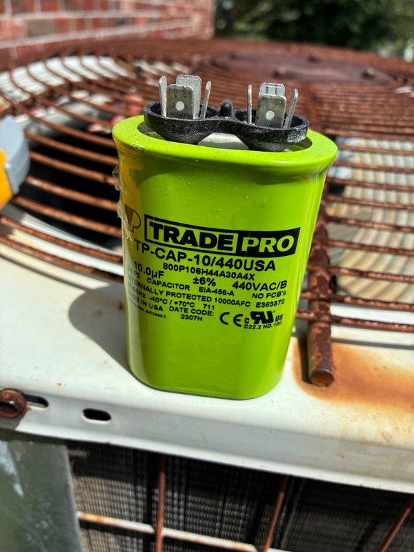 Responded to no-cooling call with indoor temperature at 80 degrees and condenser unit not operating. Upon inspection, diagnosed failed run capacitor preventing compressor operation. Replaced defective capacitor with new TRADEPRO 10 µF 440VAC dual run capacitor. Verified proper electrical connections at disconnect box, tested system operation, and confirmed condenser unit running properly with normal amperage draw and cooling cycle restored.