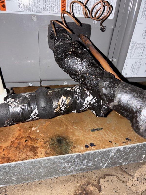 Responded to no cooling complaint with warm air discharge from HVAC system. Instructed customer to switch thermostat from cooling mode to fan-only operation to address potential evaporator coil freeze condition. Documented air handler unit installation in attic space, including refrigerant lines, electrical connections, and drainage components. Observed drain pan with visible staining and discoloration indicating previous moisture accumulation. Photographed evaporator coil assembly and associated piping for service records.