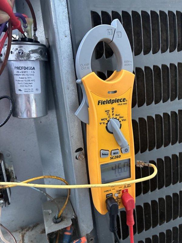 Responded to no cooling complaint with outdoor unit running but not producing cold air, particularly affecting master bathroom. Performed diagnostic testing on outdoor condensing unit using clamp meter to measure electrical values and inspected capacitor functionality. Measured amperage reading of 76.0 amps and evaluated capacitor (model PRCFD455A) connections and performance. Examined condenser coil condition and internal electrical components including wiring connections to capacitor and contactor assembly.