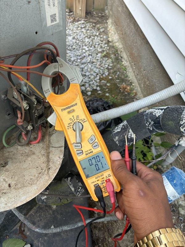 Responded to no cooling call on downstairs system. Upon arrival, accessed outdoor condensing unit and performed electrical diagnostics using clamp meter to test voltage and amperage at contactor and capacitor terminals. Inspected dual-run capacitor rated at 35+5 MFD, 370 VAC with connections to compressor and condenser fan motor. Verified thermostat set point at 70 degrees with rising indoor temperature. Conducted complete system evaluation and tested all electrical components to diagnose cooling failure.