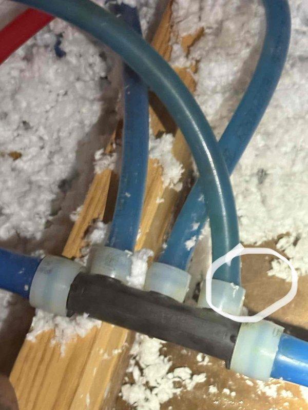 Responded to report of water leaking on ceiling in guest bathroom. Upon inspection, located condensate drain line issue in attic space above affected area. Found PVC drain lines and condensate piping with connections at central junction point surrounded by insulation on structural beam. Both HVAC systems were operating and cooling properly at time of visit. Documented piping configuration and drain line assembly with photos for reference.