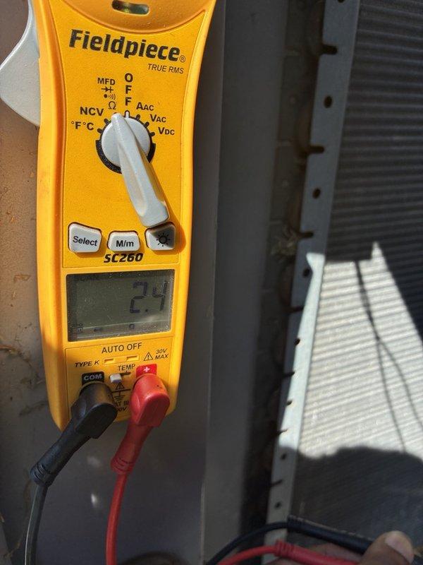 Responded to no-cooling complaint and performed diagnostic evaluation of air conditioning system. Inspected furnace combustion chamber revealing significant dust and debris accumulation on burners and chamber floor, indicating lack of routine maintenance. Utilized Fieldpiece SC260 multimeter to measure electrical parameters at outdoor condensing unit, obtaining voltage reading of 23 volts which falls significantly below standard operating voltage requirements. Low voltage condition identified as primary cause of system failure, preventing compressor and condenser fan operation. Documented equipment condition through photographs for service records. No-charge dispatch completed per customer arrangement.