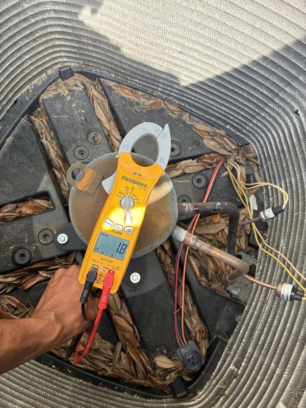 Completed comprehensive AC tune-up service on single-system residential unit for maintenance member. Performed thorough inspection of outdoor condenser unit, which exhibited heavy accumulation of dirt, debris, and organic matter throughout interior components and on condenser coils. Verified electrical connections at contactor and capacitor, noting Capcom capacitor showing surface oxidation but functioning within normal parameters. Recorded amp draw reading of 18 amps using clamp meter during operational testing. All electrical components, wiring terminals, and connections inspected and confirmed secure with no immediate concerns noted.