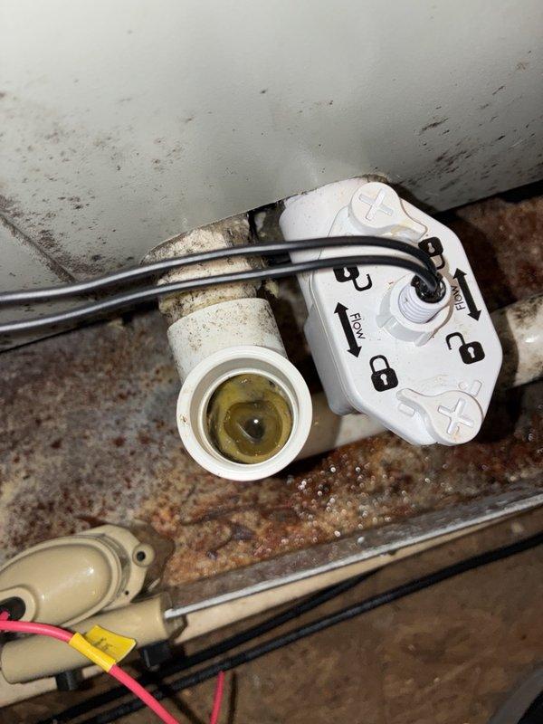 Responded to customer complaint of HVAC system running constantly with temperature fluctuations of 3-4 degrees. Inspected 2-year-old system including air handler unit and associated components. Documented equipment condition with photos showing white HVAC air handler mounted on concrete platform with visible wiring connections, control valve assembly with multiple wire terminations, and PVC condensate drain line. Observed accumulated dust, dirt, and debris throughout mechanical space on equipment surfaces and surrounding areas. Noted system configuration and control wiring connections for diagnostic evaluation of continuous run condition and temperature control issues.
