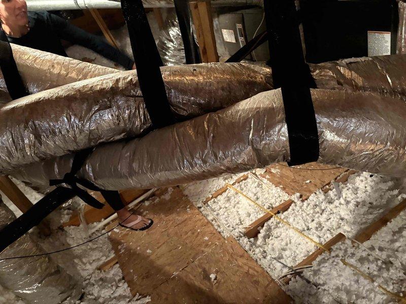 Responded to callback for excessive condensation on attic ductwork installed in July. Upon inspection, found flexible ductwork in attic space with visible sweating on exterior surfaces. Documented conditions with photos showing multiple runs of insulated flex duct suspended from ceiling joists, some sections in close proximity to each other. Verified plenum, transition, and evaporator coil installation from previous service. No water damage observed on ceiling below at time of inspection. Assessed ductwork insulation integrity and support system throughout accessible attic areas.