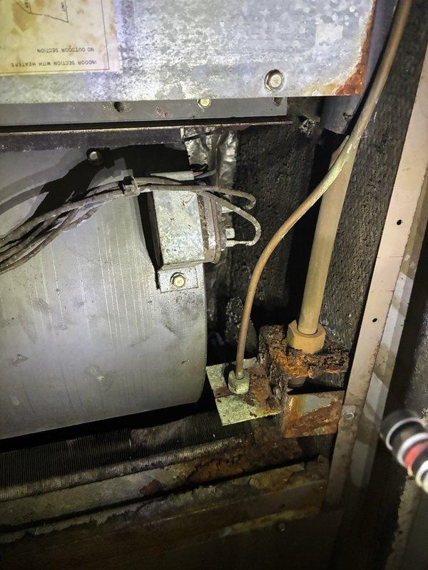 Performed a second-opinion AC tune-up and system evaluation on a 2-ton electric split system to determine repair viability versus full replacement. Inspected the indoor air handler and found significant rust and corrosion on the cabinet panel, refrigerant line fittings, and bracket, along with a dirty coil and drain pan area and aged wiring. Verified electrical operation with a clamp meter amperage check, and documented all findings with photos so the customer can pursue repair options.
