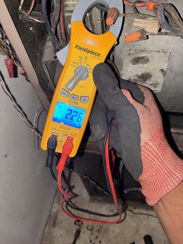 Performed a second-opinion AC tune-up and system evaluation on a 2-ton electric split system to determine repair viability versus full replacement. Inspected the indoor air handler and found significant rust and corrosion on the cabinet panel, refrigerant line fittings, and bracket, along with a dirty coil and drain pan area and aged wiring. Verified electrical operation with a clamp meter amperage check, and documented all findings with photos so the customer can pursue repair options.