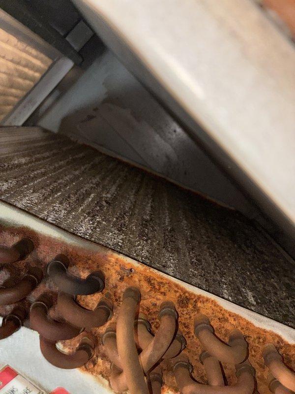 Performed a seasonal heating tune-up on one system, inspecting the air handler cabinet, evaporator coil, return bends, refrigerant line insulation, and air filter. Found heavy rust and corrosion on the coil return bends and casing, verdigris on a copper line, dirt-clogged coil fins, a dusty 16x20x1 filter, and frayed, dirty refrigerant line insulation. Documented all conditions with photos and recommend coil repair or replacement, filter replacement, and insulation repair to prevent refrigerant leaks and restore system efficiency.