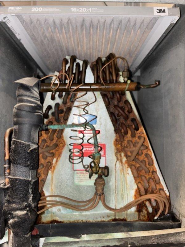 Performed a seasonal heating tune-up on one system, inspecting the air handler cabinet, evaporator coil, return bends, refrigerant line insulation, and air filter. Found heavy rust and corrosion on the coil return bends and casing, verdigris on a copper line, dirt-clogged coil fins, a dusty 16x20x1 filter, and frayed, dirty refrigerant line insulation. Documented all conditions with photos and recommend coil repair or replacement, filter replacement, and insulation repair to prevent refrigerant leaks and restore system efficiency.