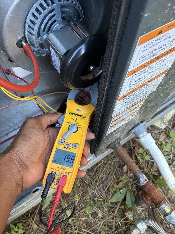 Responded to an after-hours no-heat call on the downstairs gas furnace; unit is out of warranty. Inspected the control circuitry and limit/sensor wiring, and measured amperage on the blower motor circuit with a clamp meter, which read 1.99 A AC. Noted heavy corrosion on the exterior gas supply piping.