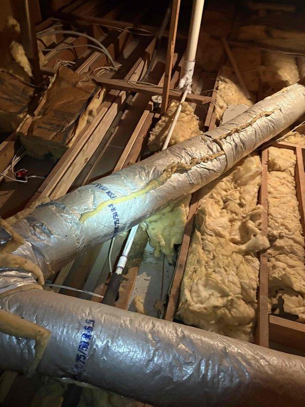 Performed full tune-up inspections on two attic-mounted HVAC systems (a gas furnace/air handler unit and its associated components) as part of a pre-sale evaluation, checking the equipment, gas supply line, condensate drain assembly with shutoff valve, and electrical connections. Found a torn seam in the foil-faced flexible supply duct with insulation bulging through the split, along with compressed and uneven attic insulation, both of which are recommended for repair to restore duct integrity and efficiency.
