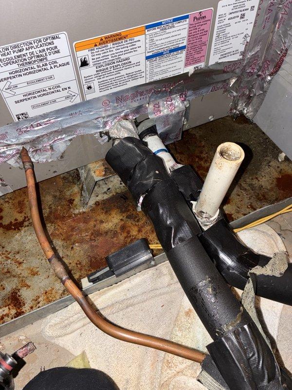 Responded to reports of a clogged condensate drain line and a non-communicating thermostat on the upstairs system. Inspected the air handler and found the drain pan heavily rusted and corroded with debris present, and checked electrical components with a clamp meter, measuring 0.61 A on the control wiring. Documented the pan corrosion and thermostat communication fault for further repair and system diagnostics.