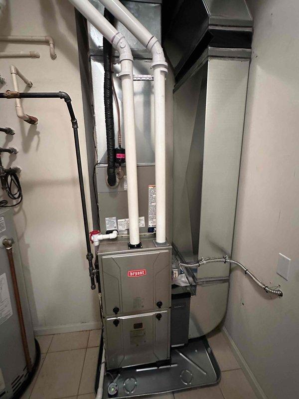 Successfully installed a complete Bryant HVAC system, including an indoor furnace unit with properly routed PVC exhaust/intake ventilation and an outdoor condenser mounted on an elevated platform. System features include appropriate ductwork connections, refrigerant lines, and electrical hookups, with all components tested for proper operation before completion.