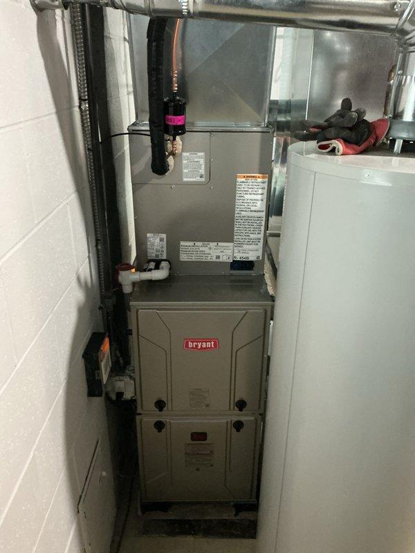 Successfully completed full system installation of a Bryant HVAC unit in utility room, featuring proper installation of metal ductwork with sealed joints, connection of PVC drain lines, and integration with existing plumbing. System includes furnace with upper and lower components, condensate pump, and all necessary connections for optimal airflow distribution throughout the residence.