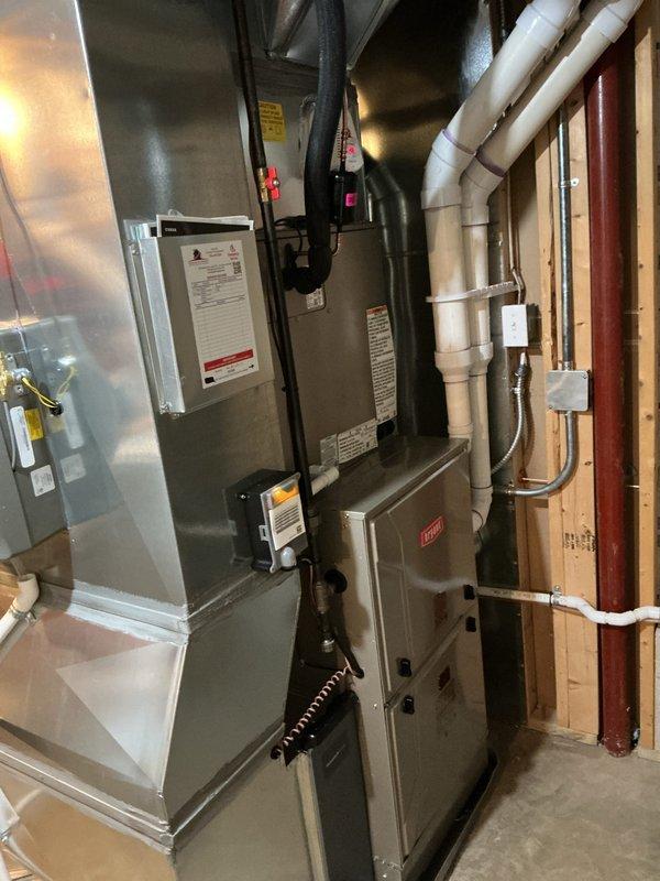Completed installation of a complete Bryant HVAC system, including furnace unit with associated ductwork and PVC ventilation piping. System was properly mounted, connected to power with successful startup verification as indicated by illuminated LED indicator, and all connections were sealed with metallic foil tape where appropriate.