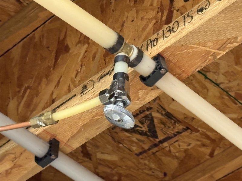 Responded to service call for leaking plumbing valve in attic space. Upon inspection, identified failed chrome-plated manifold valve at PEX piping junction point mounted to ceiling joists. Valve showed signs of wear with compromised gasket causing active leak. Documented existing installation with photos showing multi-port manifold configuration and valve assembly details. Coordinated parts procurement for replacement valve matching existing specifications. Scheduled follow-up appointment to complete valve replacement once replacement part arrives.