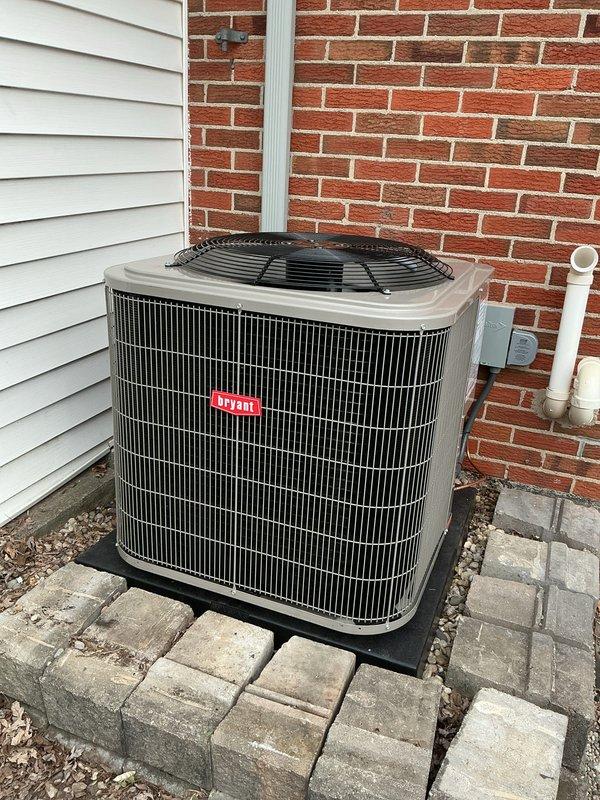 Completed installation of new Bryant air conditioning system including outdoor condenser unit and indoor evaporator coil. Mounted condenser on rubber isolation pad on exterior paver patio at corner of building, ran refrigerant lines vertically along brick wall to connect with indoor coil installed above existing Bryant furnace in mechanical closet. Installed condensate treatment system, verified all electrical connections, tested system operation and confirmed proper cooling performance.