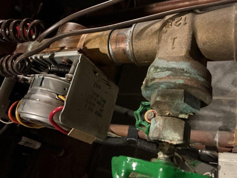 Responded to service call for boiler that would not shut off. Upon inspection, found significant corrosion and verdigris buildup on brass valve components and pipe fittings throughout the boiler system. Identified faulty zone valve with corroded electrical connections and compromised mechanical operation preventing proper system shutdown. Evaluated multiple copper pipe branches with gate valves controlling different heating zones. Noted aging infrastructure with varying degrees of oxidation on copper piping and fittings. Recommended replacement of corroded valve assembly and affected electrical components to restore proper boiler cycling and prevent continuous operation.