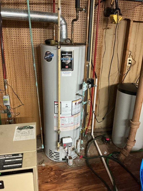 Performed comprehensive water heater tune-up on residential tanked unit located in basement utility area. Conducted thorough inspection of all plumbing connections, including inlet and outlet copper piping, temperature and pressure relief valve, and associated brass fittings at base of unit. Verified proper operation of venting system with metal flue pipe connection to ceiling. Inspected manufacturer labels and specification plates for compliance verification. Examined condition of surrounding plumbing infrastructure including PEX distribution lines mounted to pegboard walls and confirmed adequate clearances around unit per code requirements. All components found to be functioning within normal parameters. Documented equipment condition with photographic records showing water heater installation, mechanical room layout, and plumbing configuration for service history reference.