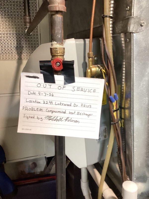 Performed routine gas furnace tune-up and system inspection at residential property. During inspection, discovered a compromised heat exchanger posing a safety hazard. Immediately tagged the unit "OUT OF SERVICE" and secured it to prevent operation until repairs can be completed. Inspected outdoor air conditioning condenser unit, confirmed proper placement on concrete pad, and verified electrical connections and conduit routing to wall-mounted disconnect box.