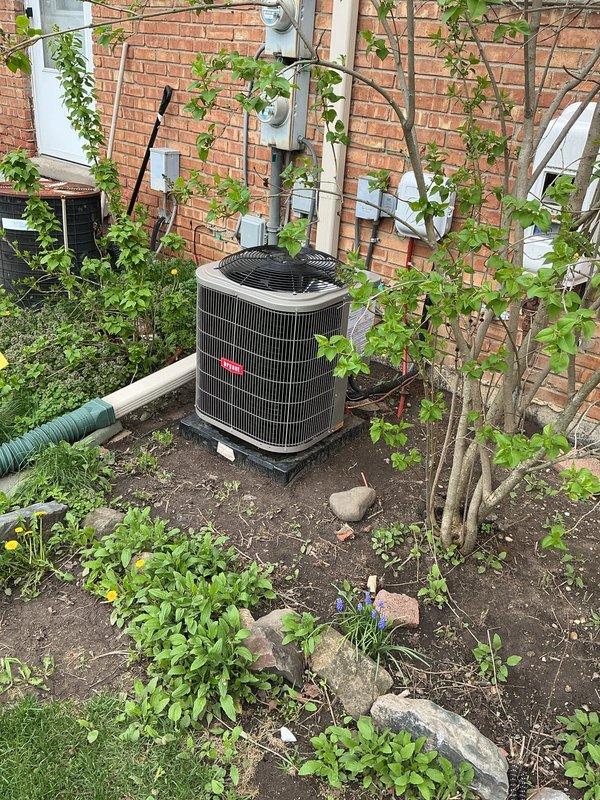 Completed system start-up and commissioning for newly installed air conditioning unit. Inspected outdoor condenser unit positioned on pad against exterior brick wall, verified proper installation of refrigerant lines, electrical connections, and drainage components. Identified damaged condensate drain hose, sourced replacement component featuring brass valve assembly with shutoff capability, and installed new hose to ensure proper system drainage and prevent water damage.