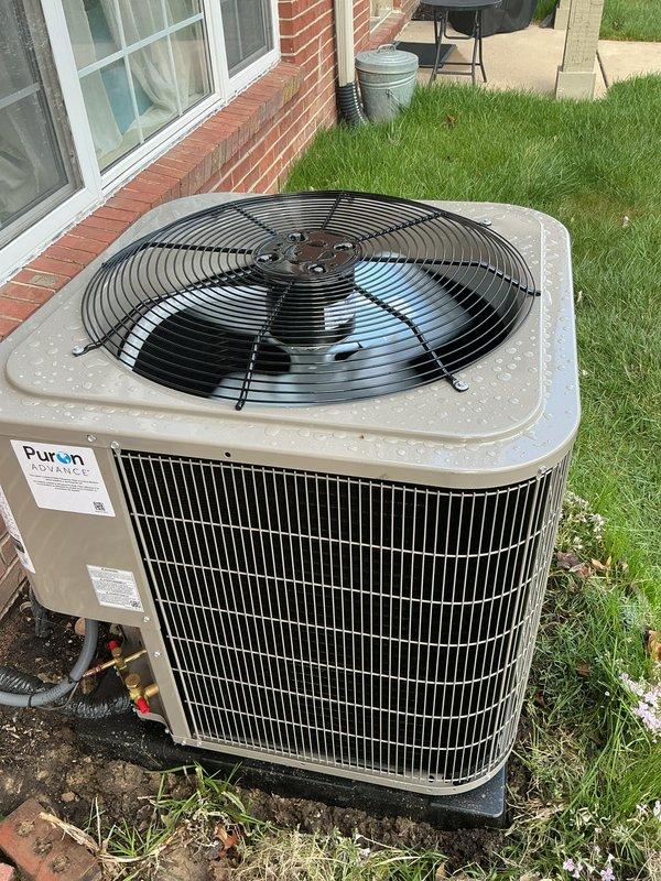 Completed full HVAC system installation including Bryant furnace, outdoor condensing unit, and humidifier in residential property. Installed furnace in interior mechanical room with proper venting and ductwork connections, including horizontal trunk line integration and condensate drainage system using white PVC piping with appropriate fittings. Mounted outdoor Puron-compatible air conditioning condenser unit on concrete pad adjacent to brick exterior, connected refrigerant lines, and verified proper electrical connections. All components installed per manufacturer specifications with appropriate clearances and code compliance. System tested and operational.