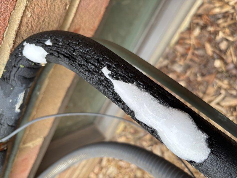 Responded to no-cooling complaint on 33-year-old air conditioning system with reported foam discharge from exterior insulated refrigerant line. Upon inspection, found severe ice accumulation on suction line insulation, indicating refrigerant system failure consistent with unit age and condition. Documented extensive frost buildup and system configuration with photos for customer records, confirming system has exceeded expected service life and requires replacement rather than repair.