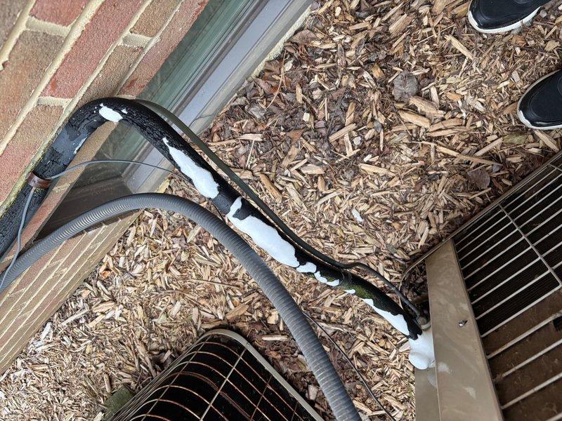 Responded to no-cooling complaint on 33-year-old air conditioning system with reported foam discharge from exterior insulated refrigerant line. Upon inspection, found severe ice accumulation on suction line insulation, indicating refrigerant system failure consistent with unit age and condition. Documented extensive frost buildup and system configuration with photos for customer records, confirming system has exceeded expected service life and requires replacement rather than repair.