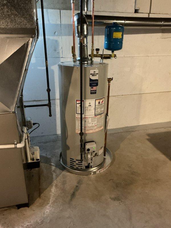Completed full installation of new HVAC furnace, water heater, and humidifier system in residential basement utility area. Successfully installed cylindrical water heater with proper drip pan placement, connected all copper supply lines, installed expansion tank with wall mounting, and ensured all plumbing connections meet code requirements. Installed furnace unit with appropriate venting through exterior wall using white PVC exhaust pipe, integrated humidifier into HVAC system, and verified all mechanical systems are properly connected and operational.