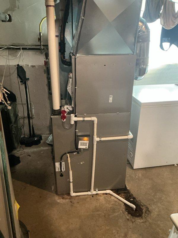 Completed installation of new air conditioning condenser unit and evaporator coil system. The outdoor condenser unit was professionally mounted on a concrete pad against the exterior brick wall with proper electrical connections and refrigerant lines installed, while the indoor evaporator coil was integrated with the existing furnace system in the basement utility area. All components were tested for proper operation, refrigerant charge verified, and system confirmed to be cooling efficiently per manufacturer specifications.