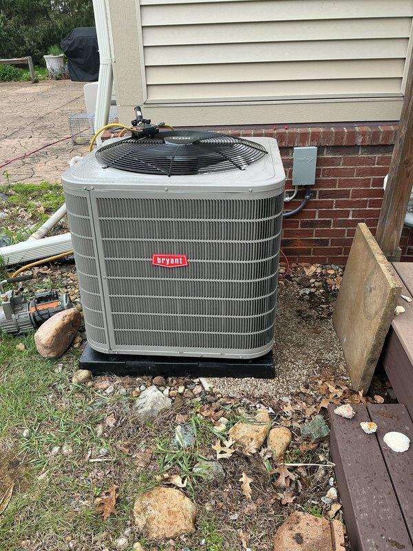 Completed installation of new Bryant air conditioning condenser unit and evaporator coil system. The outdoor condenser was positioned on a level gravel pad against the home's exterior with proper clearances maintained for airflow and serviceability. Inside the residence, installed the new evaporator coil in conjunction with the existing Lennox furnace, establishing refrigerant line connections between indoor and outdoor components. Installed PVC intake and exhaust venting with proper routing and support, completed all electrical connections to the control box mounted on exterior wall, and pressure-tested the refrigerant system to verify leak-free operation before final charging to manufacturer specifications.