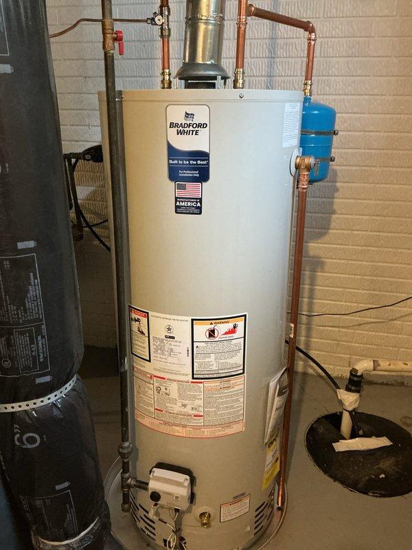 Installed a 50-gallon Bradford White gas water heater in basement utility room, including all necessary connections and safety components. Connected copper supply lines with brass fittings and valves to the top of the unit, installed blue expansion tank on the right side with proper copper piping connections, and ensured pressure relief valve was properly installed with appropriate discharge piping. All plumbing connections were secured and tested for proper operation and leak-free performance per manufacturer specifications and local code requirements.