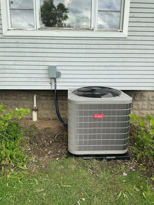 Completed full HVAC system installation including Bryant furnace, air conditioning condenser unit, and humidifier in residential property. Installed furnace in basement mechanical room with proper venting via white PVC piping, established electrical connections with flexible metallic conduit, and integrated ductwork assembly to air handler section. Mounted outdoor Bryant condenser unit on concrete pad against exterior wall with appropriate clearances, installed electrical disconnect box, and ran conduit from disconnect to unit. Connected refrigerant lines between indoor and outdoor components, installed condensate drainage system, and integrated humidifier into duct system. All equipment installed per manufacturer specifications with proper labeling visible on units. System tested and confirmed operational.
