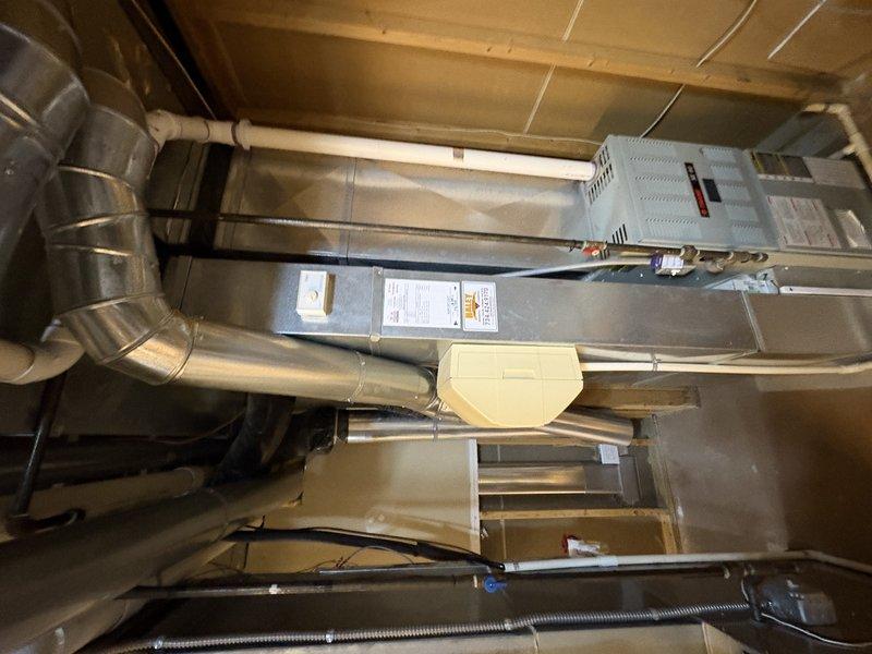 Responded to water leak reported beneath ground floor air handler unit installed in 2018. Upon inspection, identified source of water accumulation in utility area. Documented existing HVAC system configuration including air handler, ductwork connections, and drainage components to assess leak origin and determine appropriate corrective action under parts warranty coverage.