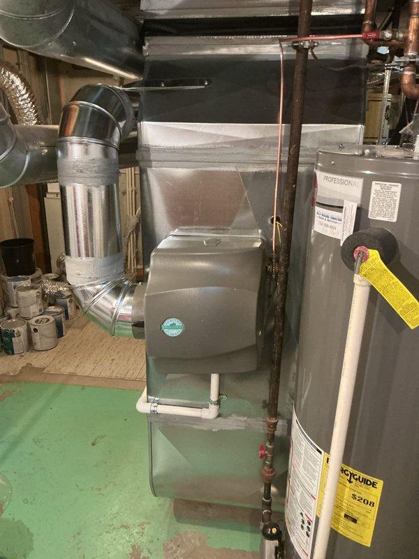 Completed installation of new furnace and humidifier system in residential basement mechanical room. Installed gray metal furnace unit with proper venting using white PVC condensate drainage piping and metallic ductwork connections. Integrated humidifier into system and verified all connections, ensuring proper operation of both units alongside existing water heater and plumbing infrastructure.