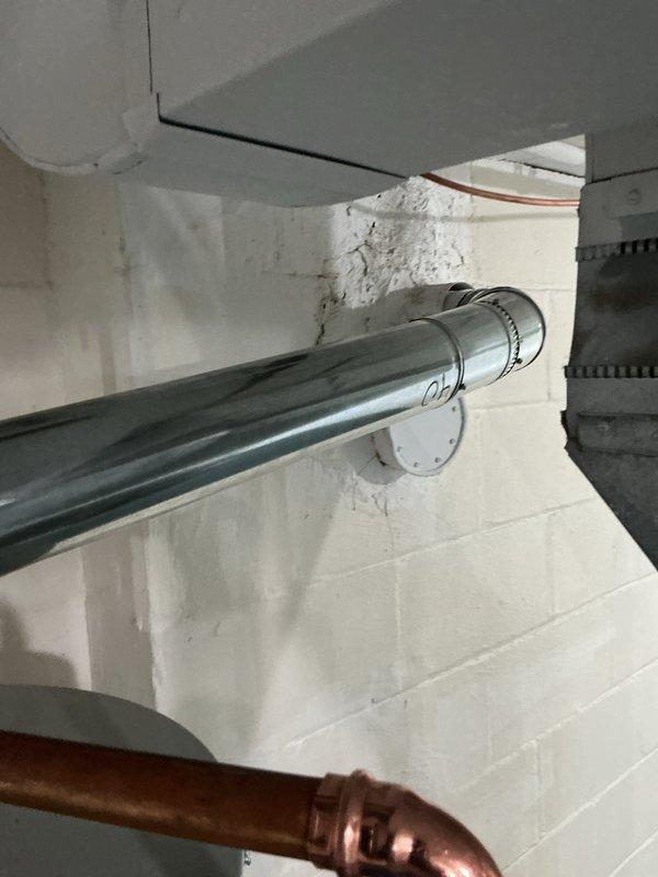 Completed installation of a 50-gallon Bradford White natural gas water heater, model RE250T6N, with 40,000 BTU/hr input rating. The unit was properly positioned and secured in the basement utility area, with all gas connections, water supply lines, and venting configured according to manufacturer specifications and local code requirements. Copper supply piping was connected to ensure proper water flow, and the exhaust venting system was installed through the existing ductwork penetration in the wall structure. All safety labels and operational instructions remain visible and accessible on the unit for future reference.