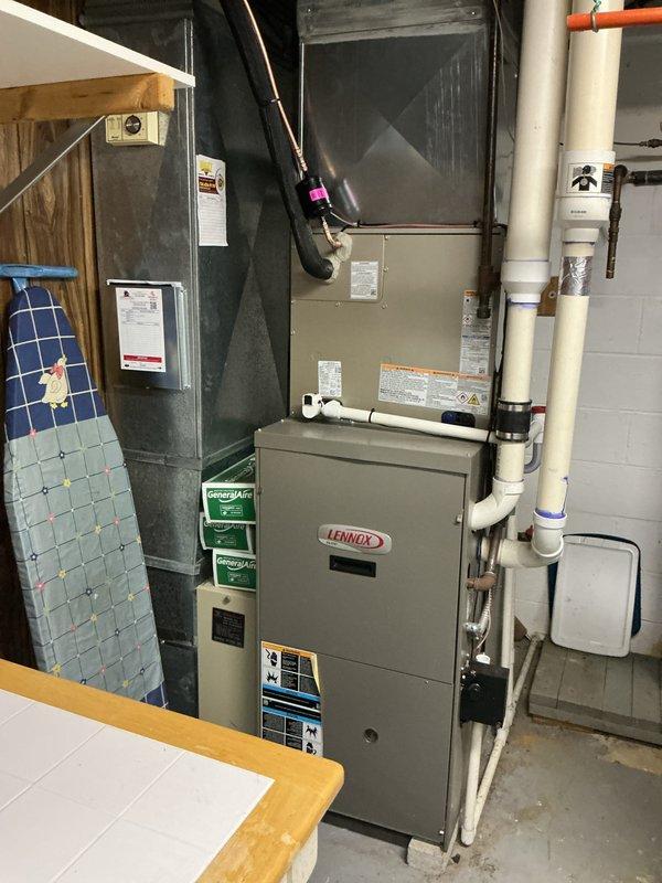 Completed installation of new Bryant outdoor air conditioning condenser unit and Lennox indoor air handler system. Positioned condenser on pad against exterior wall with proper clearances, ran electrical conduit from junction box to unit, and established refrigerant line connections. Installed indoor air handler above existing furnace in basement mechanical room, integrated ductwork connections with black flexible duct, and verified all electrical components including disconnect switch were properly mounted and operational. System tested and confirmed operational with no leaks detected in refrigerant lines.