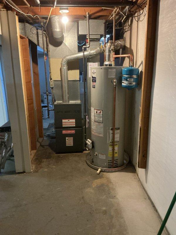 Completed installation of 5/8" tanked water heater in basement utility room. Connected all hot and cold water supply lines using copper piping with proper brass fittings and installed blue expansion tank on copper piping above unit. Installed pressure relief valve with discharge piping, verified all connections for proper seal, and confirmed system operational with no leaks detected.