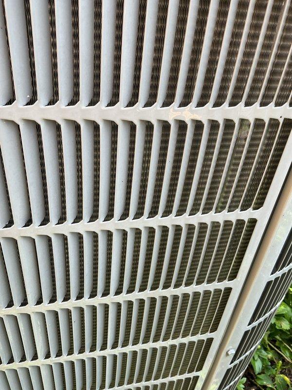 Completed scheduled air conditioning tune-up and preventative maintenance service on residential outdoor condenser unit. Performed comprehensive system inspection, noting accumulated dirt and debris on condenser coil fins with visible discoloration and environmental buildup affecting heat transfer efficiency. Unit operational and positioned on proper pad with adequate clearance from surrounding vegetation and structures.