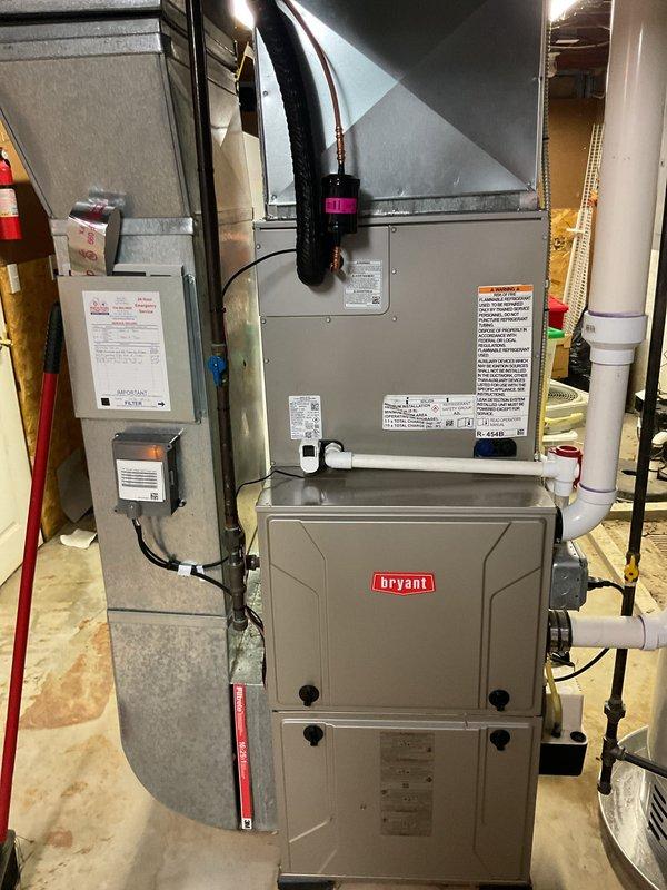 Completed installation of new Bryant air conditioning system including outdoor condensing unit and indoor evaporator coil. Outdoor unit was positioned on pad against exterior brick wall with proper clearances, electrical disconnect box mounted, and refrigerant lines connected. Indoor evaporator coil was installed above existing Bryant furnace in basement mechanical room, integrated with existing ductwork and plenum system. All refrigerant lines were run, system was evacuated, charged to manufacturer specifications, and tested for proper operation. Electrical connections completed to code, condensate drainage configured with PVC piping, and all safety controls verified functional.
