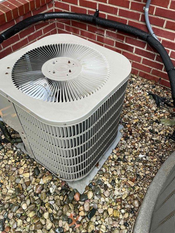 Completed annual AC maintenance tune-up on aging outdoor condensing unit positioned against exterior brick wall. Performed comprehensive system inspection, cleaned condenser coils and fan assembly, checked refrigerant levels and electrical connections, verified proper operation of radial fan and compressor components. Unit operating within normal parameters following routine preventive maintenance service.