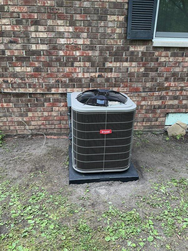 Completed installation of new air conditioning condenser unit and evaporator coil at residential property. Unit was positioned on rubber isolation pad against brick exterior wall, with all refrigerant lines connected, electrical wiring terminated, and system tested for proper operation including airflow and cooling cycle functionality.