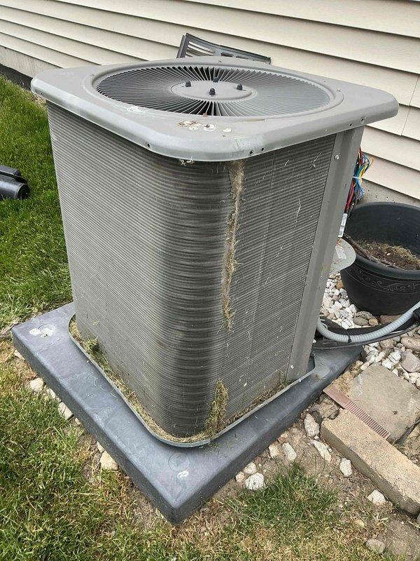 # HVAC Maintenance - Cooling System Service

Performed routine maintenance on outdoor air conditioning condenser unit experiencing reduced cooling efficiency due to significant debris accumulation and environmental contamination. Upon inspection, found substantial dirt, dust, and debris buildup throughout condenser coil fins, with heavy blockage in multiple sections restricting proper airflow and heat exchange capability. Observed green moss and algae growth at unit base, dirt streaking on exterior casing, and general weathering consistent with extended operation without maintenance.

Thoroughly cleaned condenser coil fins to remove accumulated debris and restore optimal airflow through heat exchange surfaces. Addressed contamination blocking fin spacing to ensure proper system operation and efficiency. Cleaned exterior surfaces and removed biological growth from unit base and mounting area. Verified refrigerant line connections and inspected electrical disconnect for proper operation.