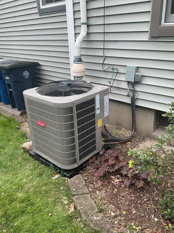 Completed full HVAC system installation including Bryant air conditioning condenser unit, furnace, and whole-home humidifier. Positioned outdoor AC unit on equipment pad against exterior wall with proper clearance, connected refrigerant lines and electrical service from meter panel, and installed condensate drain line with PVC piping routed down exterior siding. Interior installation included furnace setup in utility area with associated gas connections, venting, and humidifier integration into ductwork system. All equipment tested and verified operational, system commissioned and ready for service.