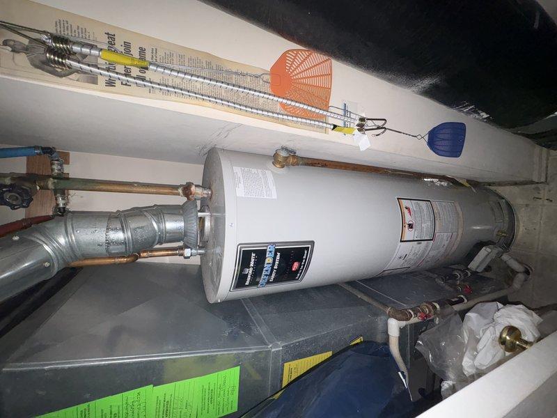 Responded to water heater leak originating from fitting or pipe connection at top of unit. Upon arrival, inspected tanked water heater and associated plumbing connections in utility space. Identified source of leak at upper piping assembly where copper supply lines connect to water heater inlet/outlet. Assessed ball valves, shut-off connections, and pipe fittings for signs of failure or deterioration. Tightened loose fitting and verified integrity of connections. Tested system operation and monitored for additional leaks. All connections secured and leak resolved.