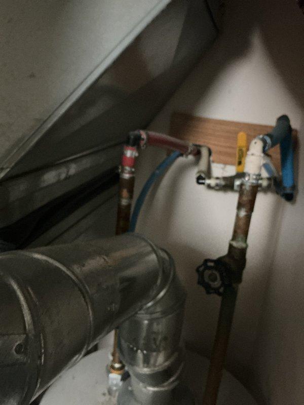 Responded to water heater leak originating from fitting or pipe connection at top of unit. Upon arrival, inspected tanked water heater and associated plumbing connections in utility space. Identified source of leak at upper piping assembly where copper supply lines connect to water heater inlet/outlet. Assessed ball valves, shut-off connections, and pipe fittings for signs of failure or deterioration. Tightened loose fitting and verified integrity of connections. Tested system operation and monitored for additional leaks. All connections secured and leak resolved.